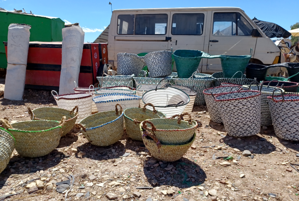 Assorted woven baskets and storage bins displayed outdoors beside a white van Tinghir Souk